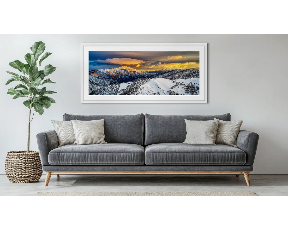 Alpine Magic. Alpine snow sunrise wall art, in a white frame, above a couch.