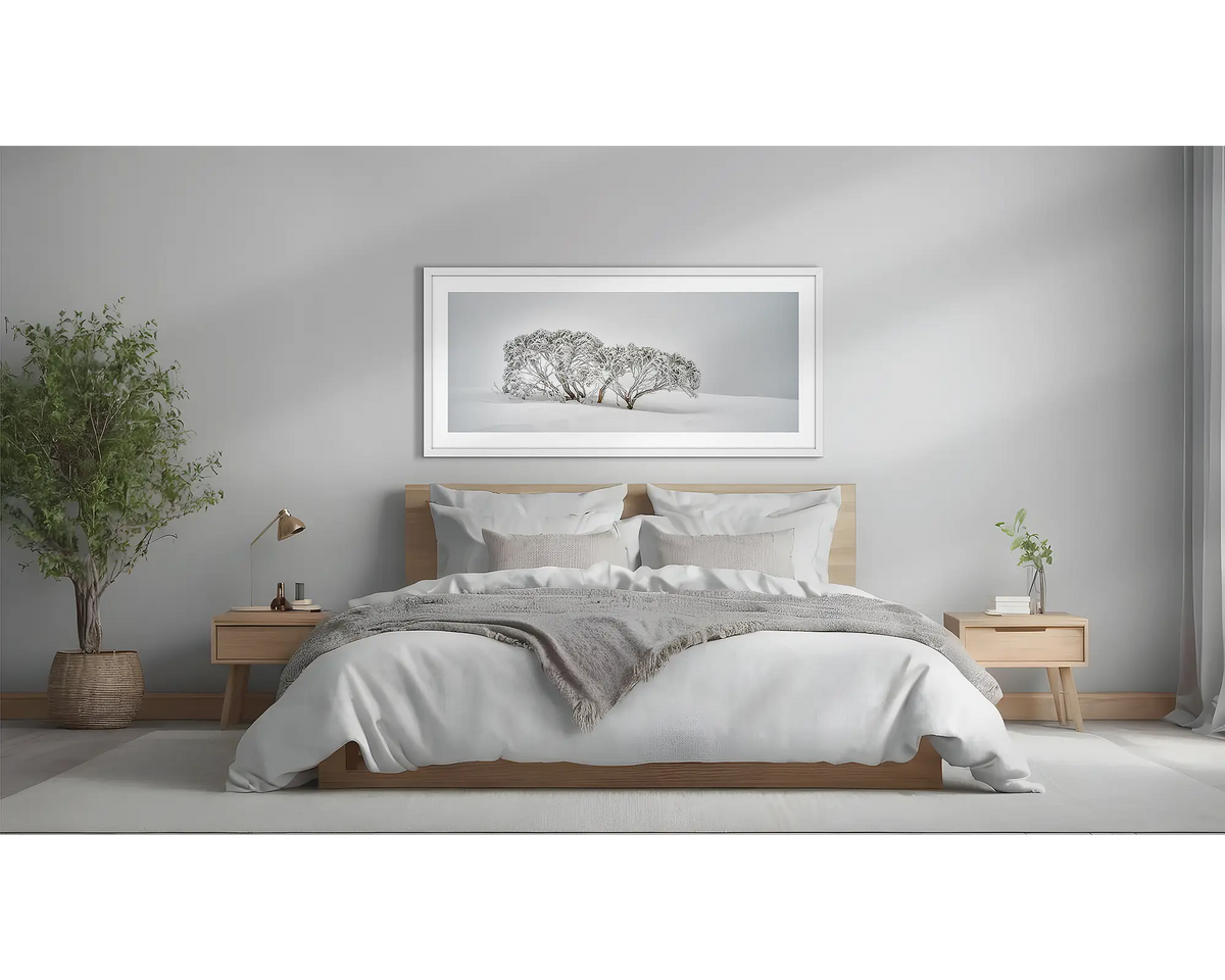 Alpine Spirit. Snow gum wall art, framed in a white frame, above a bed.  