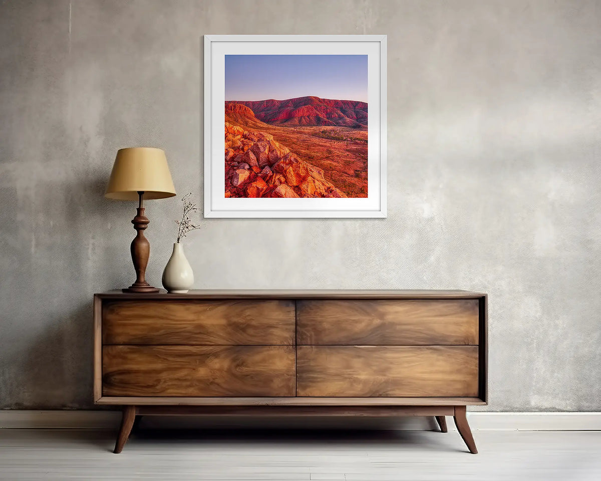 Ancient Dawn. Square, outback wall art print, with a white frame, above a side table. 