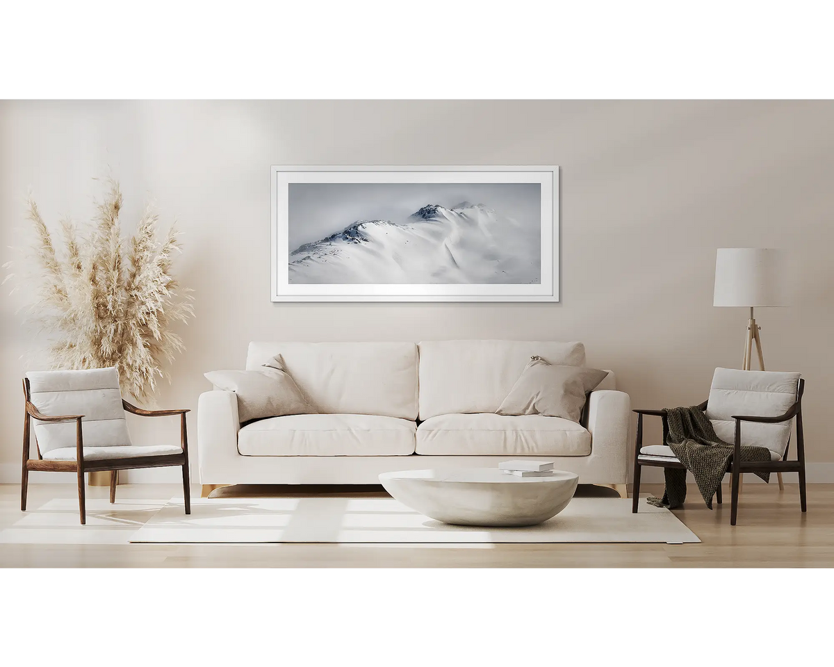 Ascent. Winter snow artwork in a white frame, above a couch. 