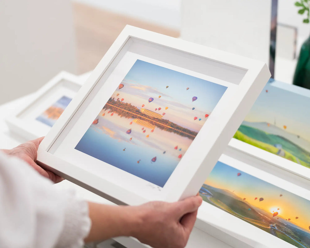 Balloon Spectacular. National Library at and balloons, Canberra. Small framed print with white frame being held.