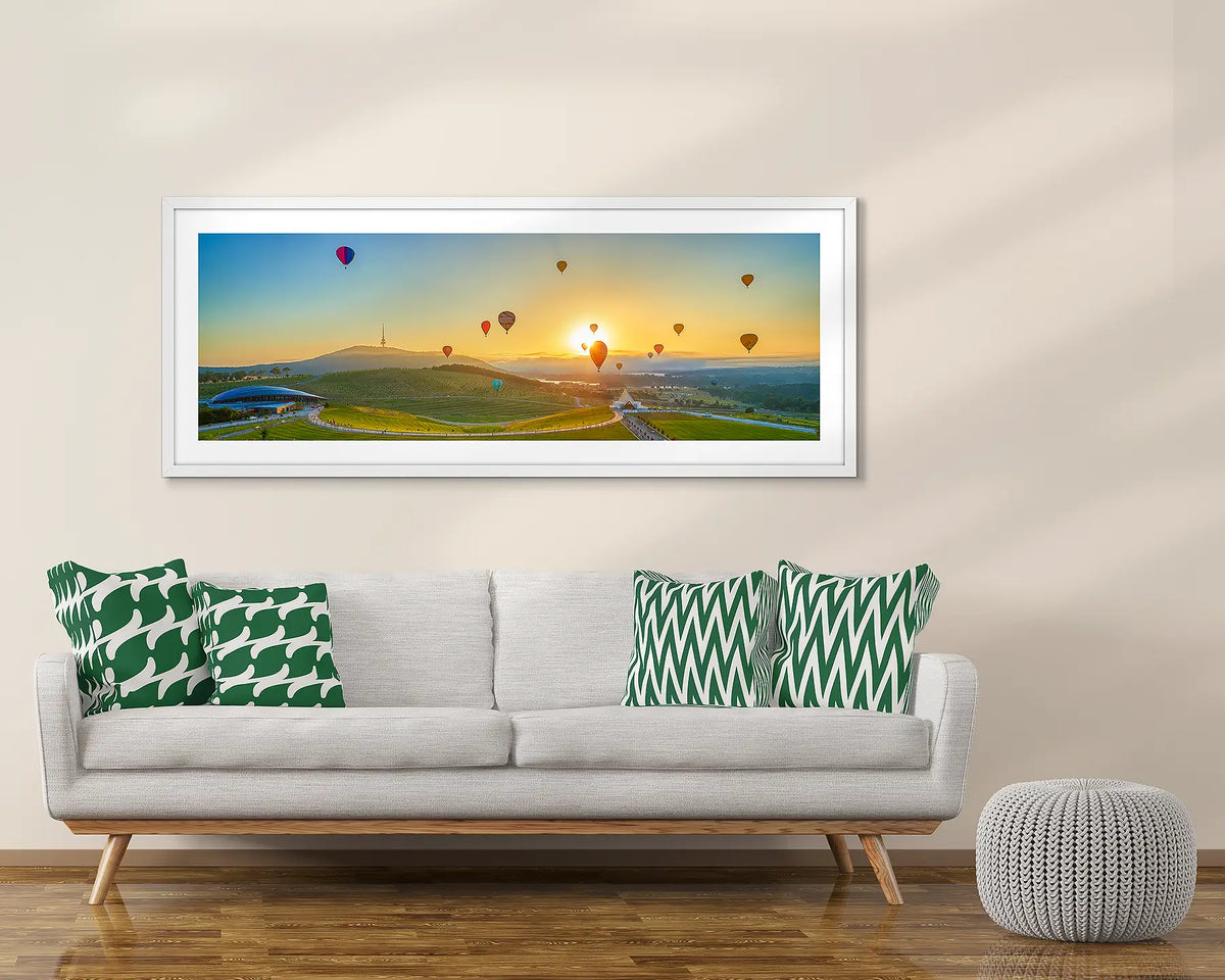 balloon Sunrise. Canberra balloon artwork, framed in white, above a couch. 