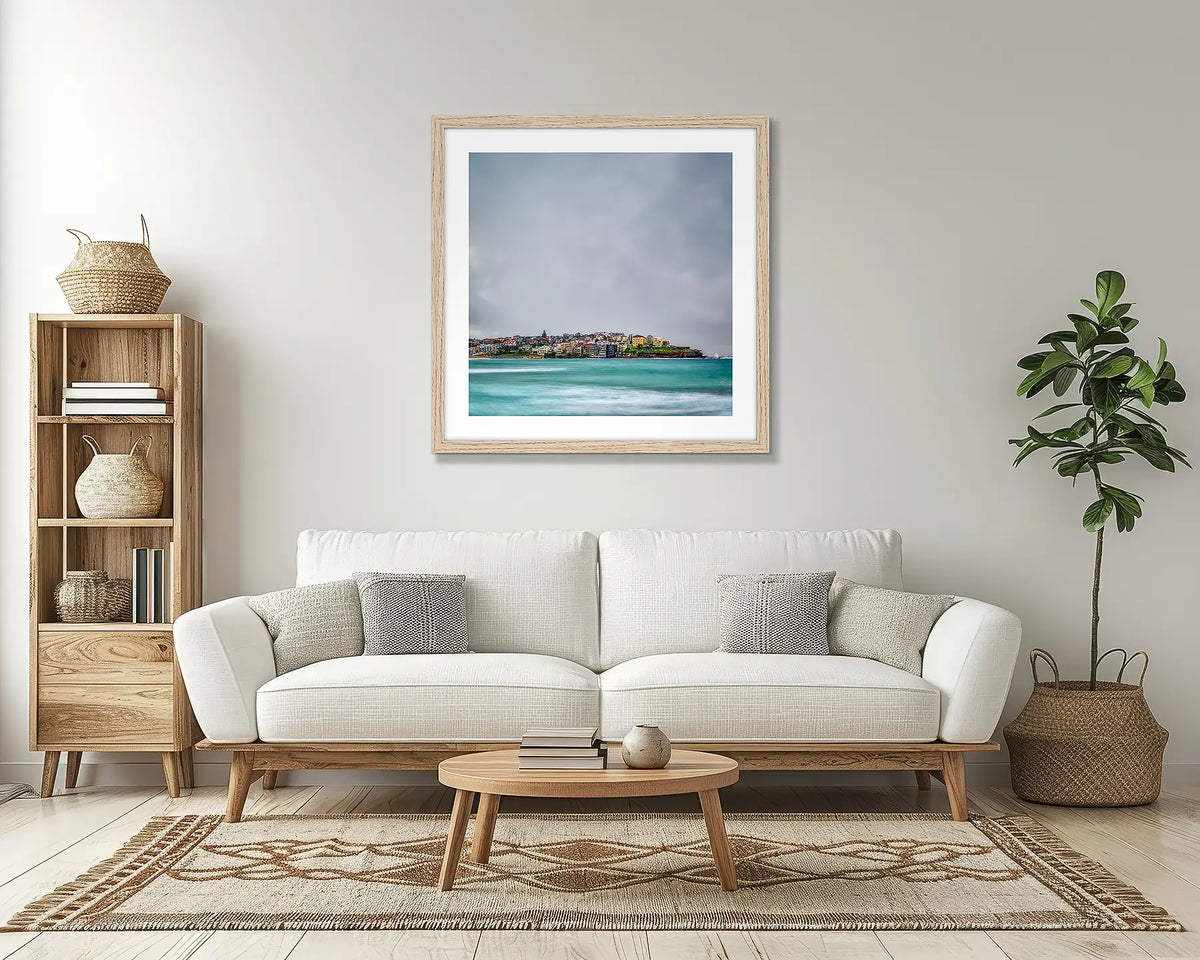 Bondi Views. Sydney wall art print, with a Tassie oak frame, above a couch.