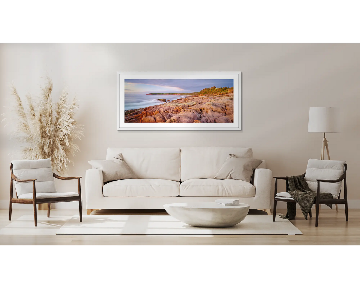 Breaking Through. Coastal artwork with a white frame, above a couch. 