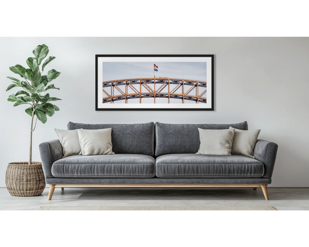 Bridge Climb. Framed wall art print of Sydney Harbour Bridge, with a black frame, hung above a couch. 