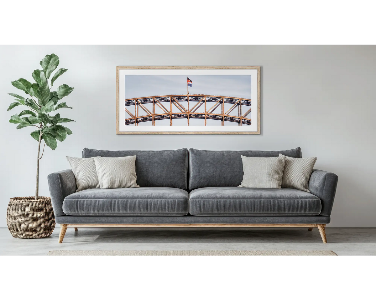 Bridge Climb. Framed wall art print of Sydney Harbour Bridge, with a timber frame, hung above a couch. 