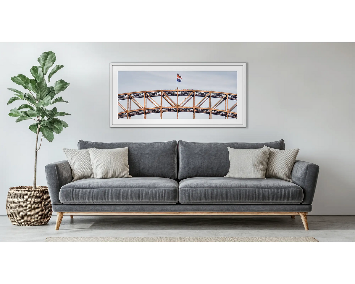 Bridge Climb. Framed wall art print of Sydney Harbour Bridge, with a white frame, hung above a couch. 