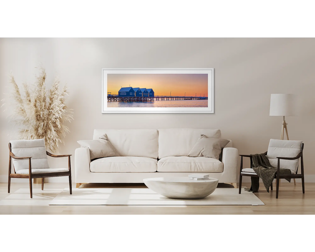 Busselton Sunset. Wall art with a white frame, above a couch. 