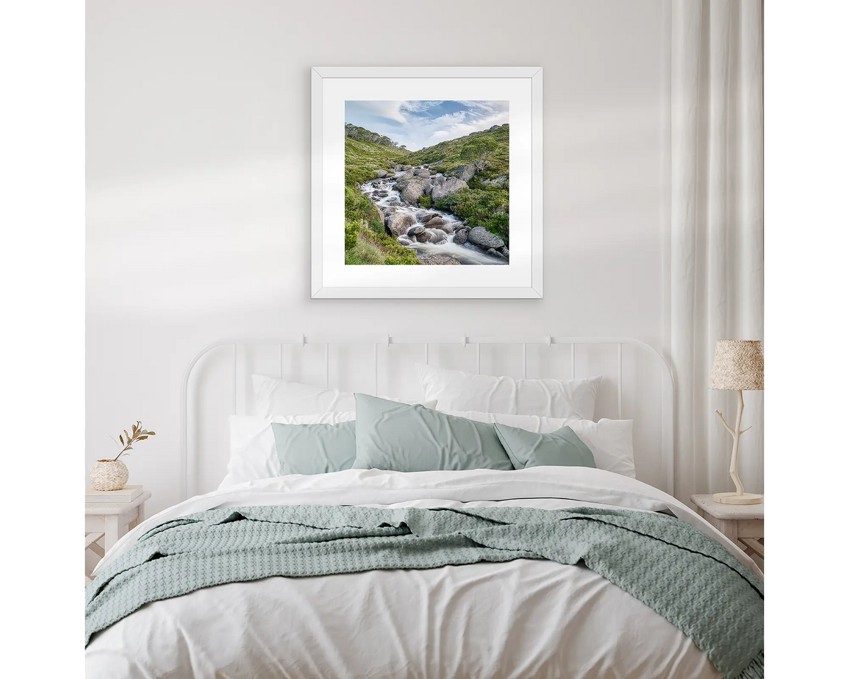 Cascade. Snowy Mountains artwork hanging above a bed, with white and gum leaf linen.