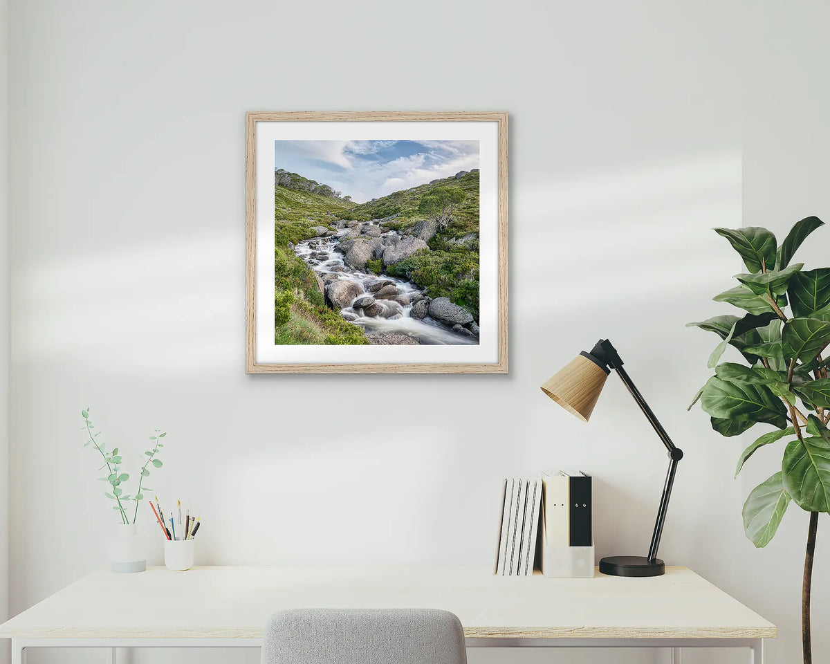 Cascade. Snowy Mountains artwork, hanging above a desk, with a timber frame.