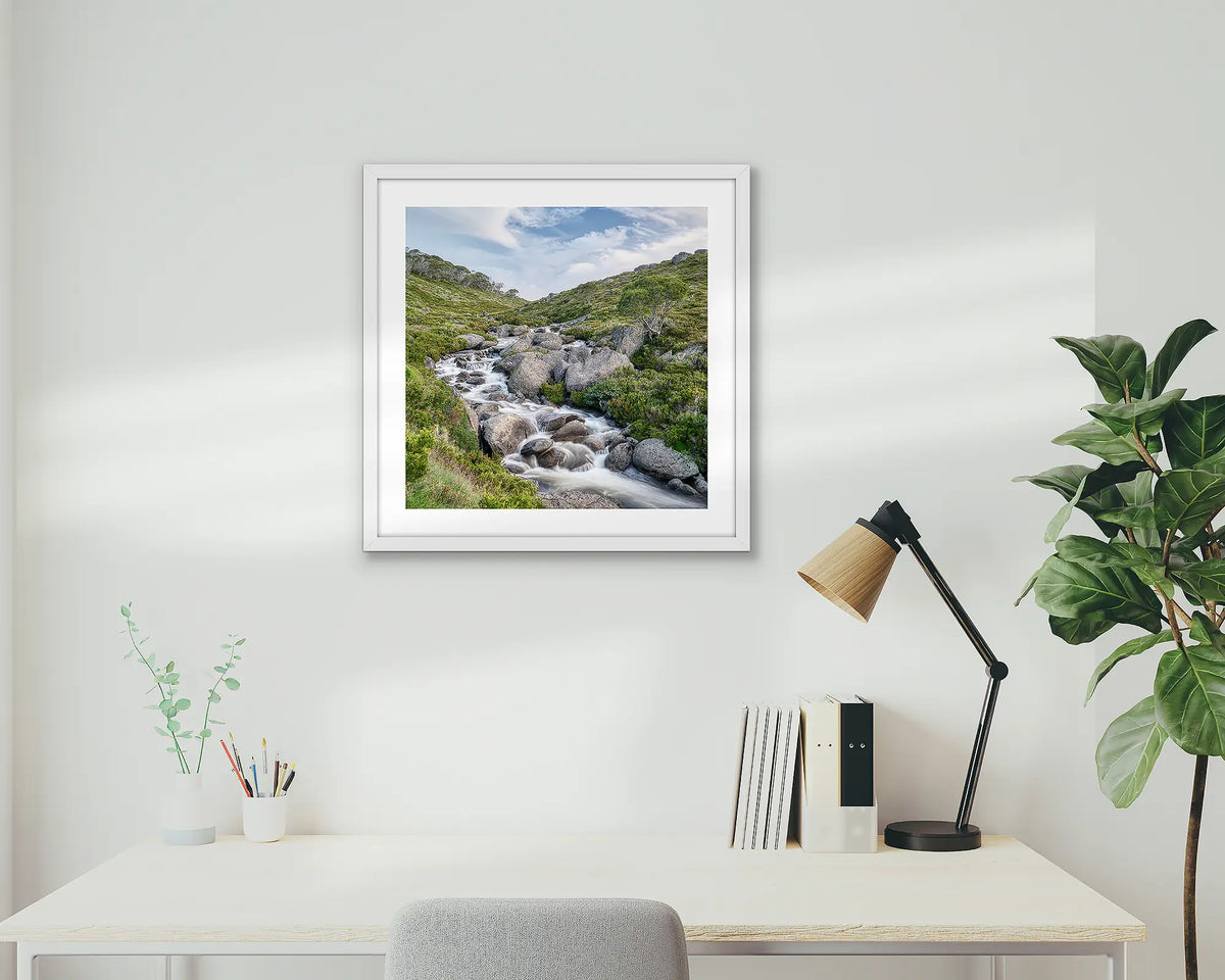 Cascade. Snowy Mountains artwork, hanging above a desk, with a white frame.