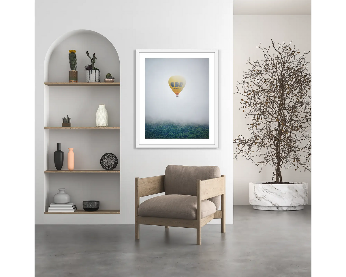 CBR Balloon. Visit Canberra wall art print, with a white frame, hung above a chair.