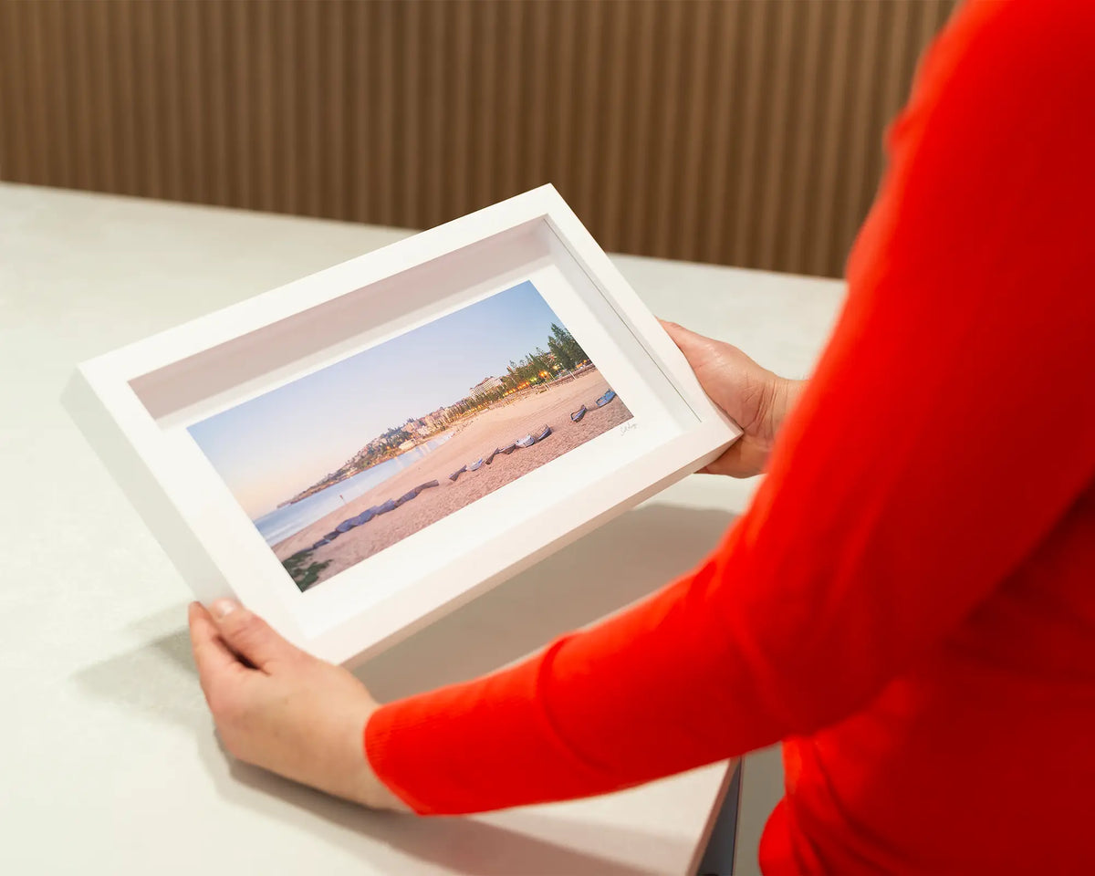 Coogee Sands. Beach sunrise, small frame print, with a white frame, on a desk. 