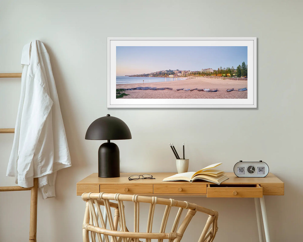 Coogee Sands. Sunrise at Coogee beach wall art print with white frame hung above small desk.