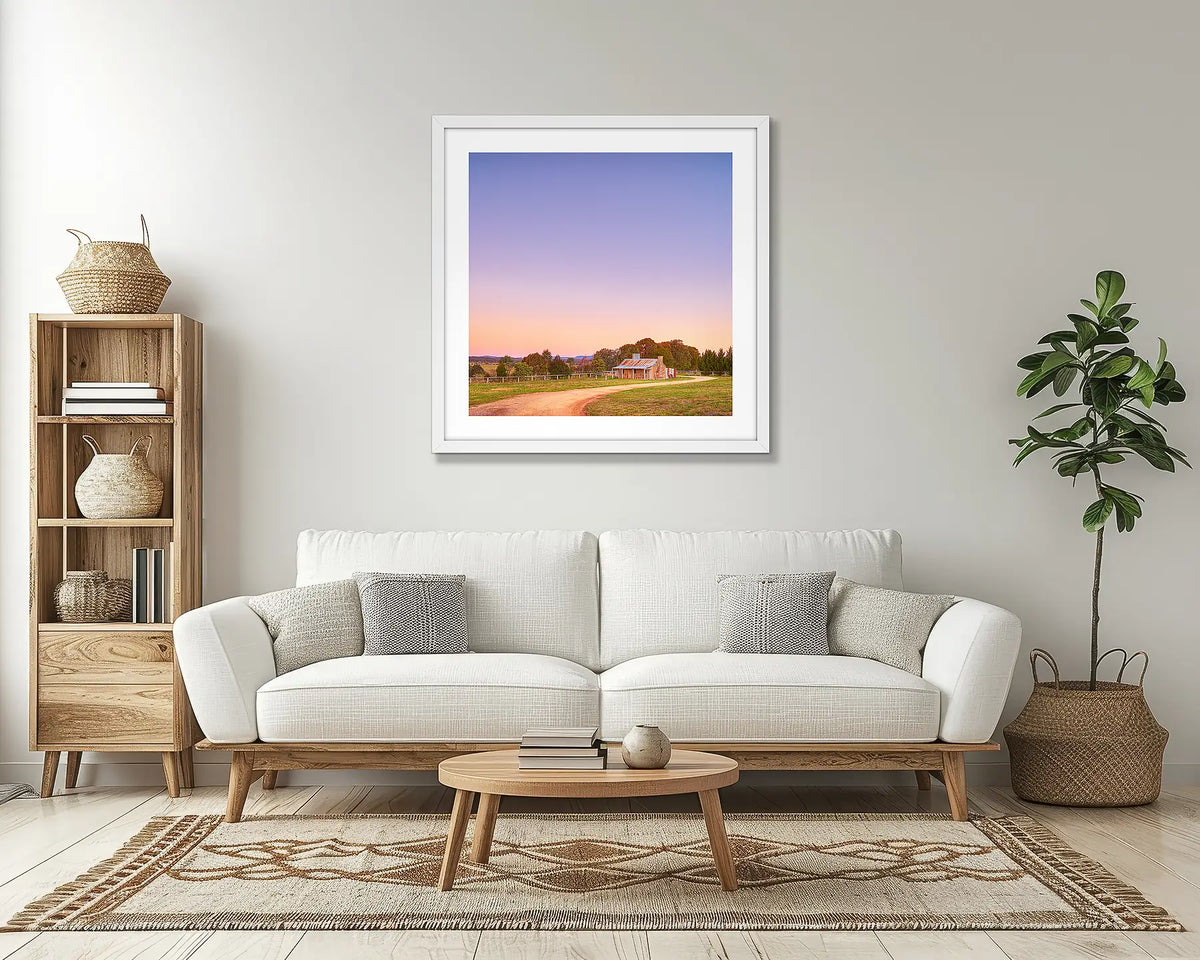 Country Charm. Rural farm wall art print, with a white frame, above a couch. 