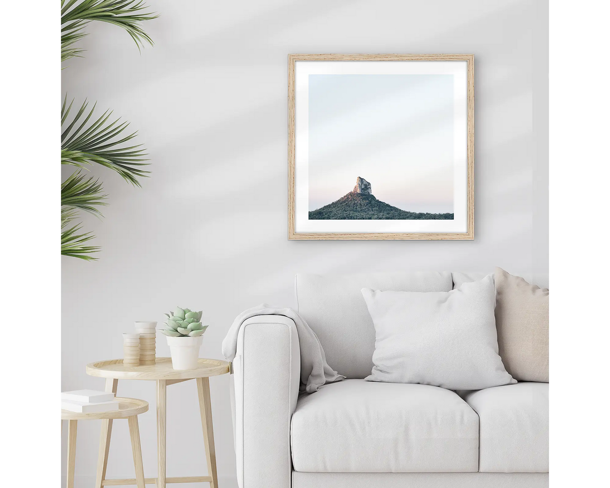 Crookneck. Framed Glasshouse Mountains wall art print, with a timber frame, hung above a couch.