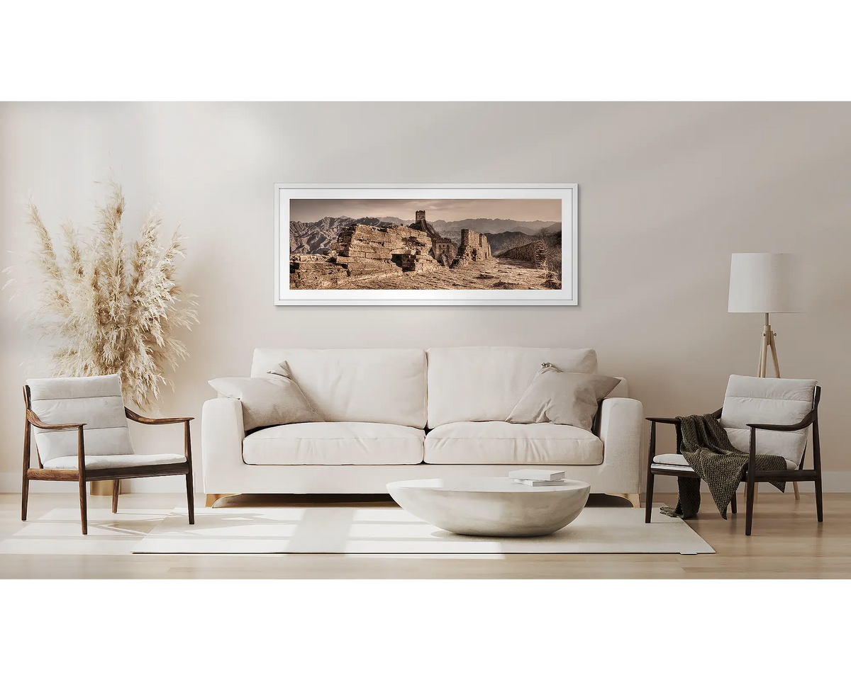 Crumbling Wall. Great Wall of China artwork with a white frame, above a couch. 