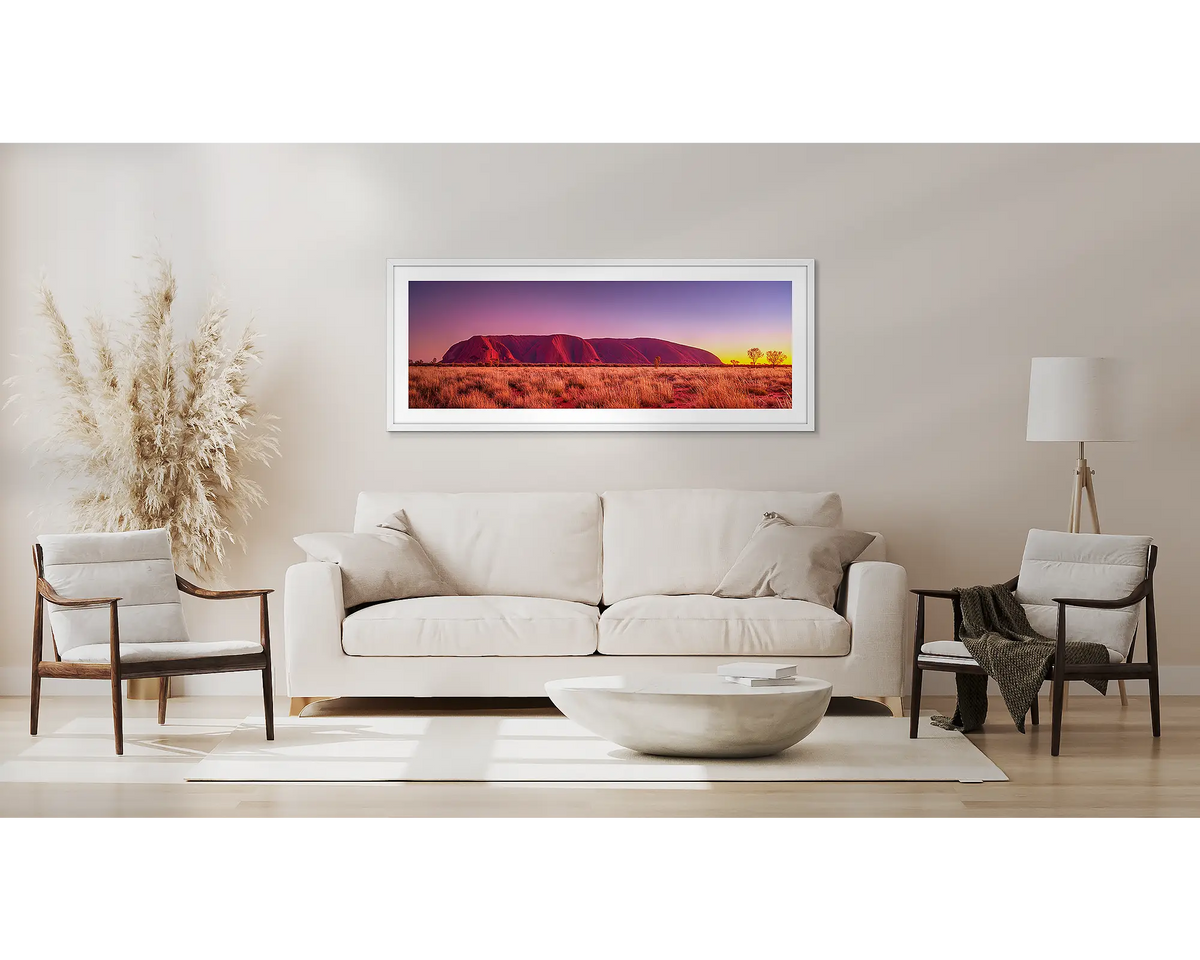 Desert Awakening. Uluru sunrise wall art, with a white frame, above a couch. 