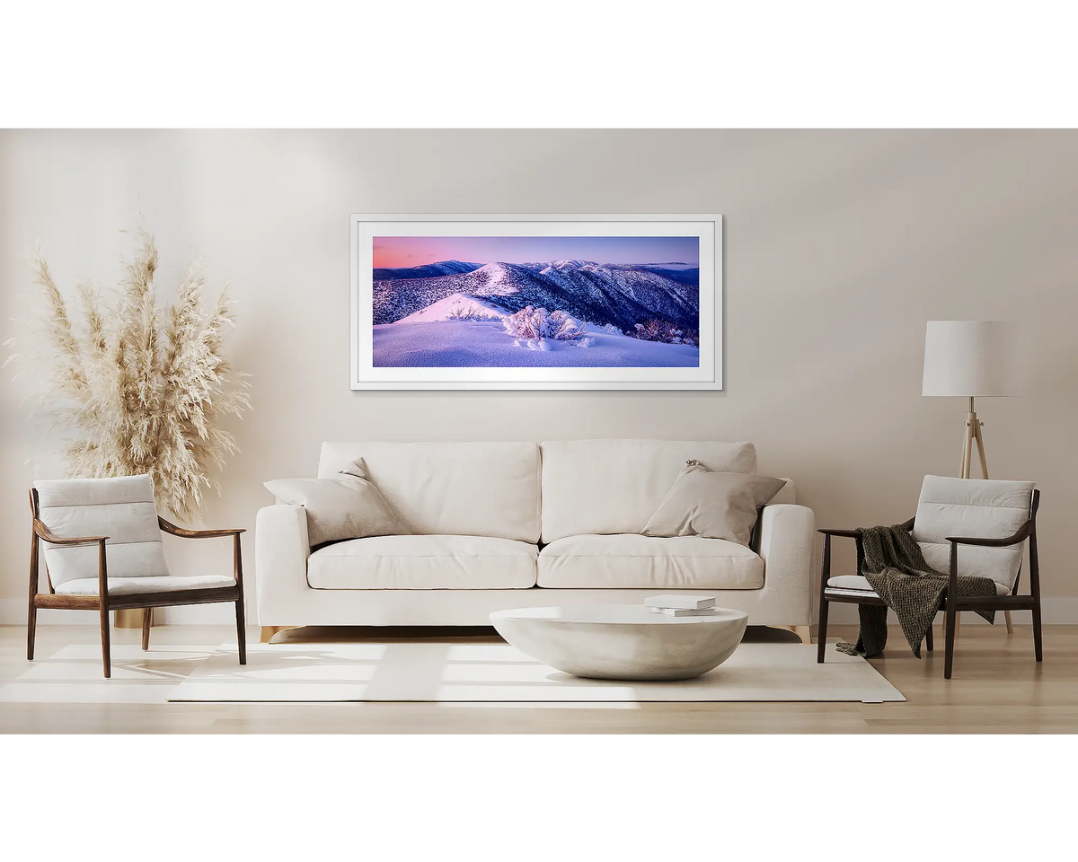 Distance. Winter alpine wall art in a white frame, above a couch. 