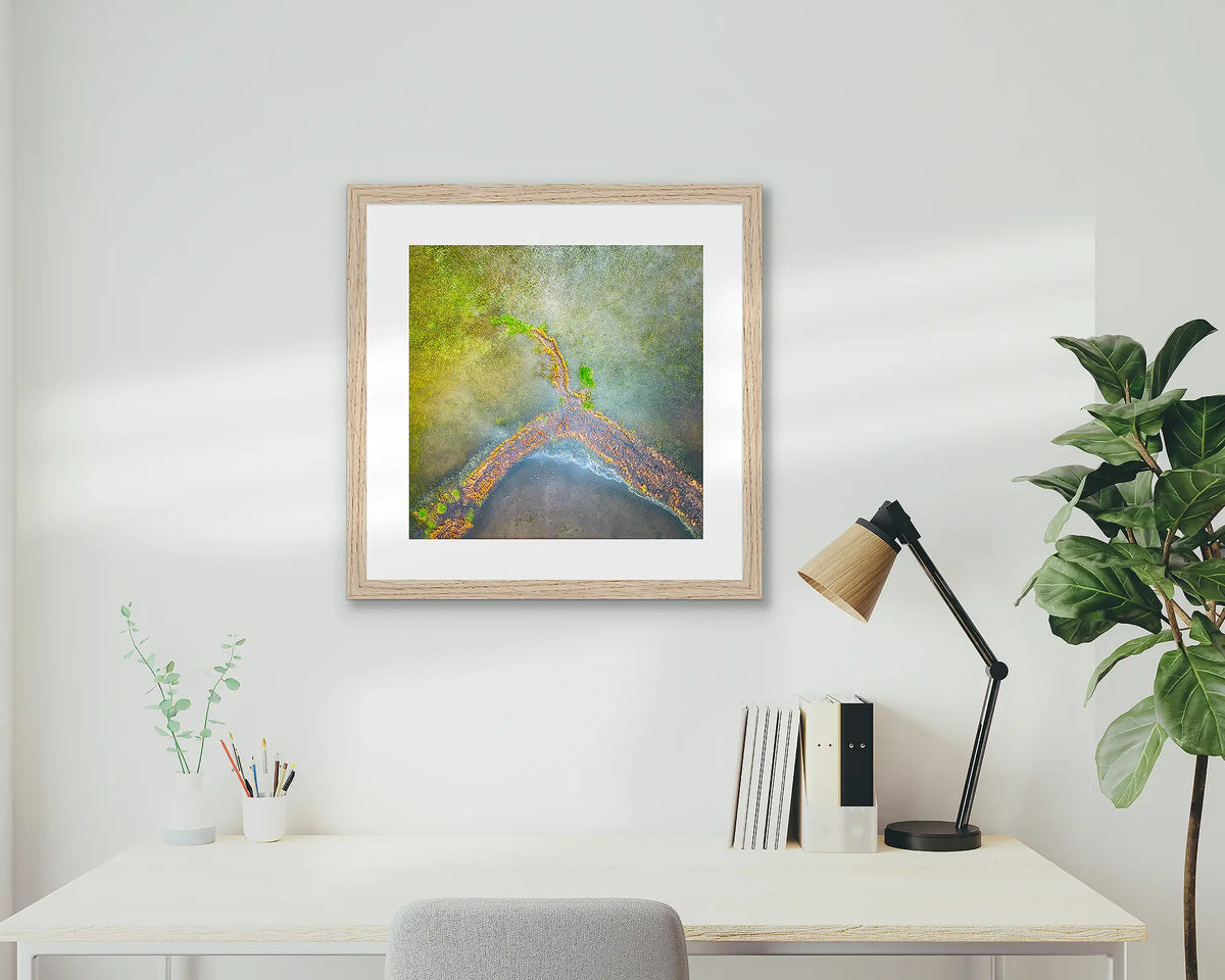 Divergent. Aerial view of Lake George, wall art print with an oak frame, on a study wall. 