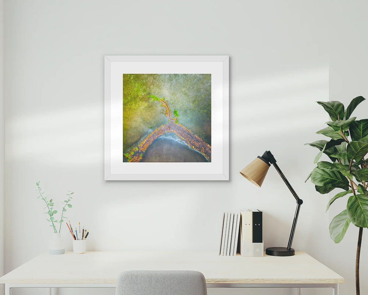 Divergent. Aerial view of Lake George, wall art print with a white frame, on a study wall. 