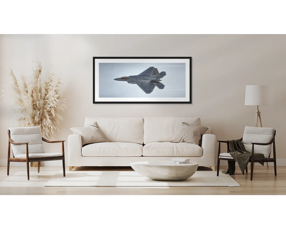 Dominating the Skies. F-22 Raptor aviation wall art print, with a black frame, above a couch. 