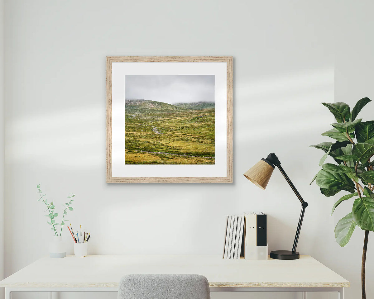 Drizzle. Snowy Mountains framed artwork, with an oak frame, on a study wall. 