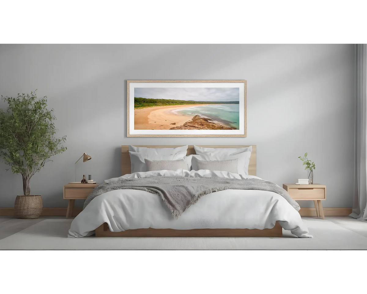 Durras Calm. Coastal wall art framed in a Tasmanian Oak frame, above a bed.