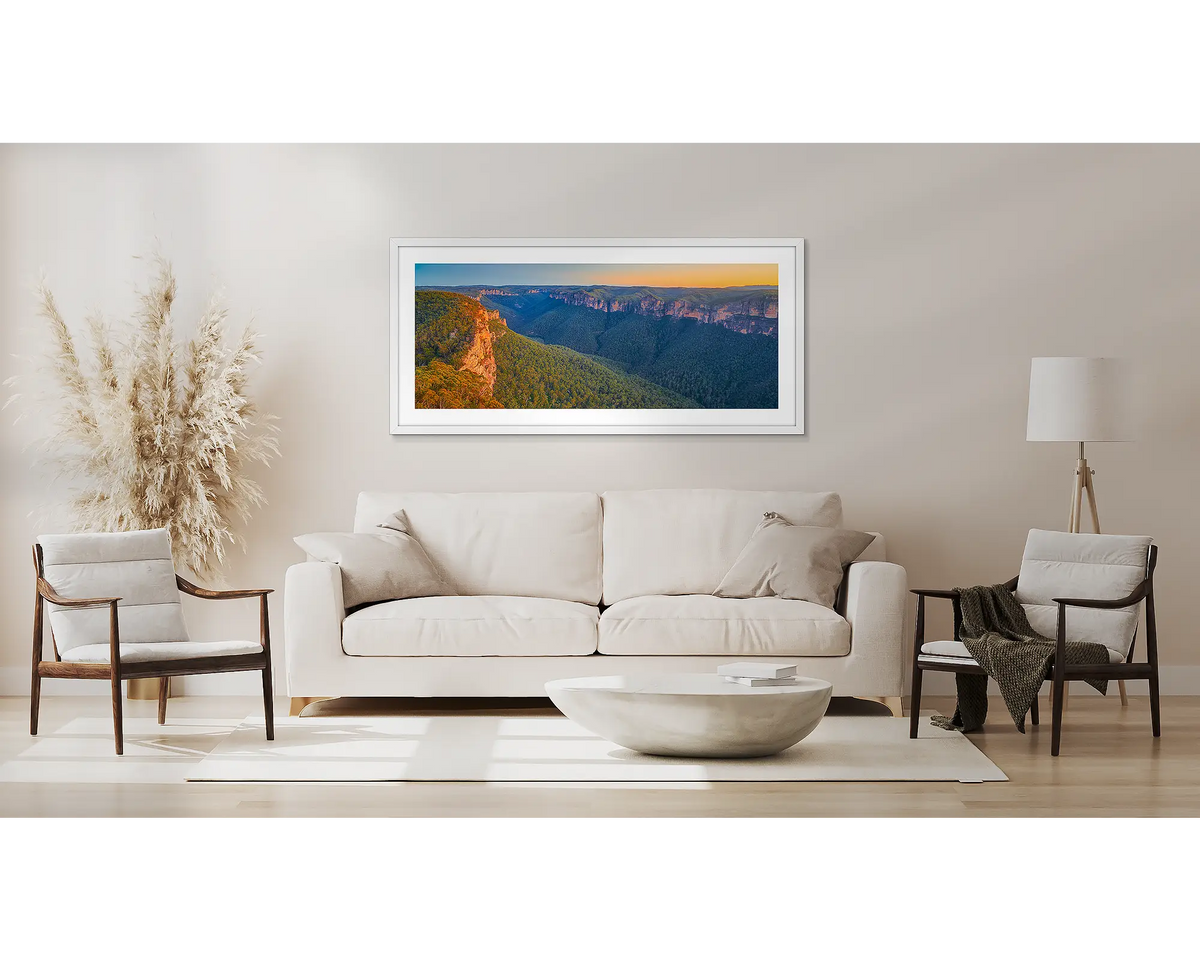 Escape from the City. Blue Mountains wall art print, in a white frame, above a couch. 