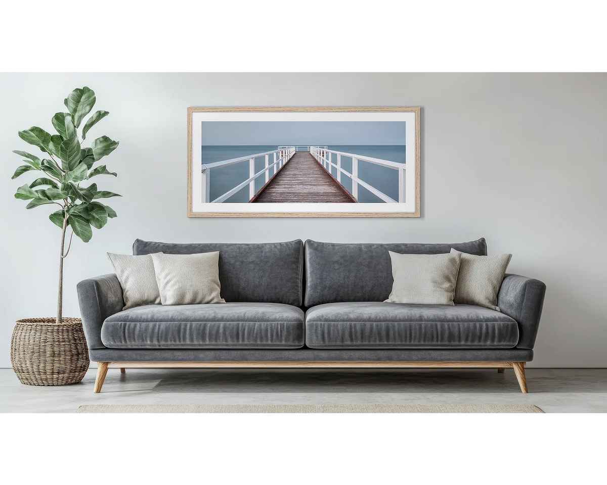 Evening Calm. Framed wall art print of a jetty, with a timber frame, hung above a couch.