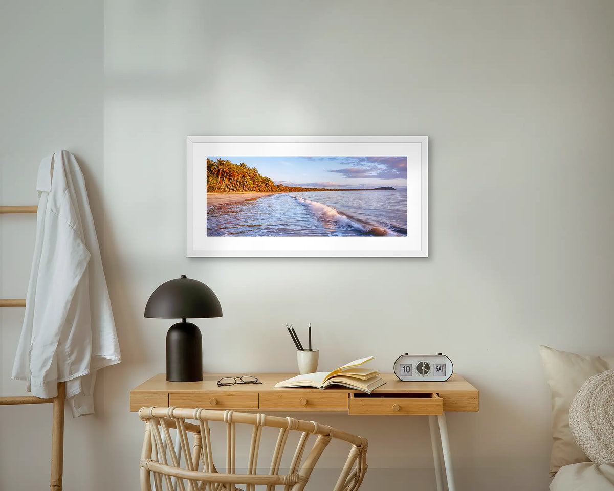 Four Mile Sunrise. Port Douglas, coastal wall art print with a white frame, above a bedside table.