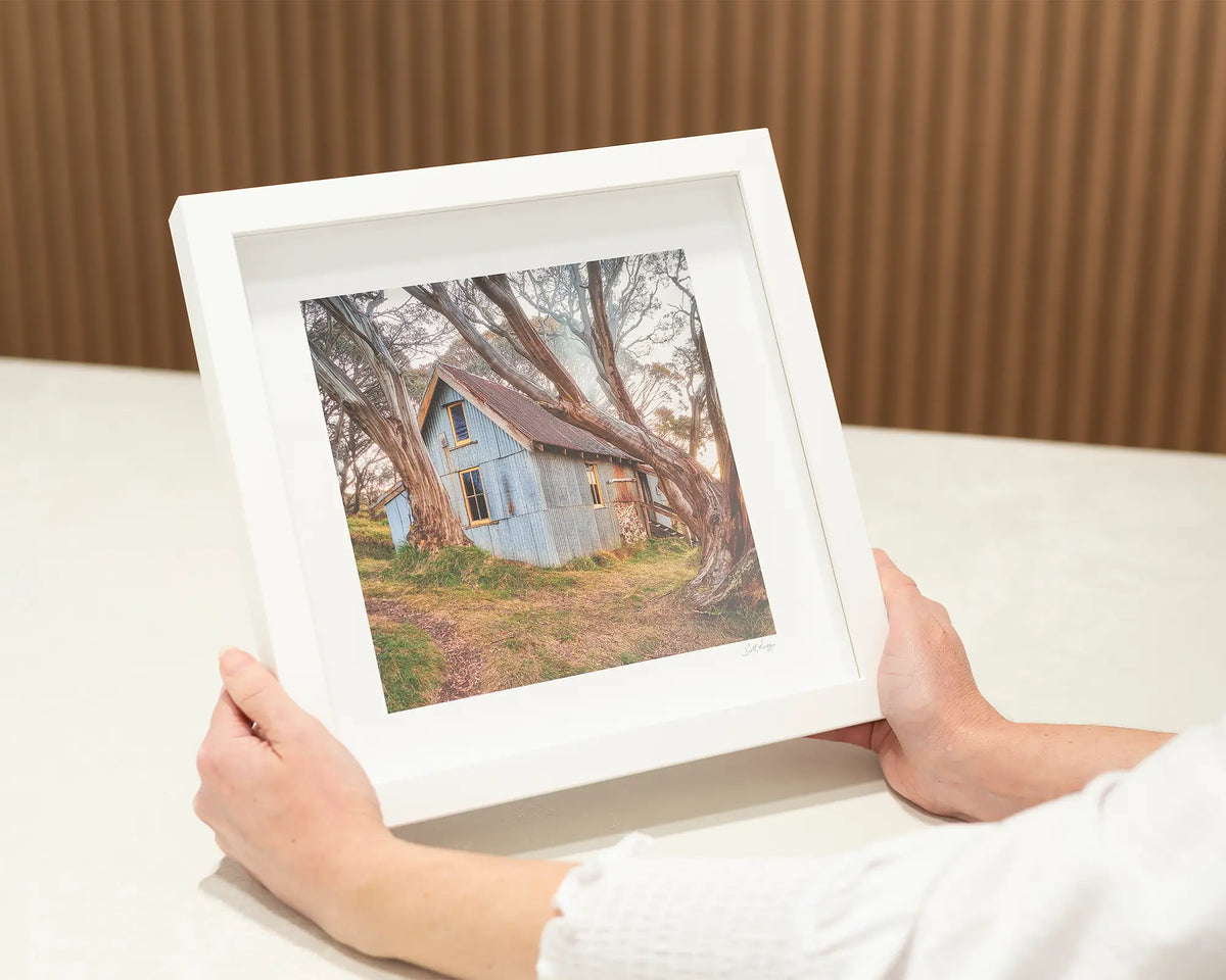 High Country Life. Alpine hut, small, square framed print with a white frame.