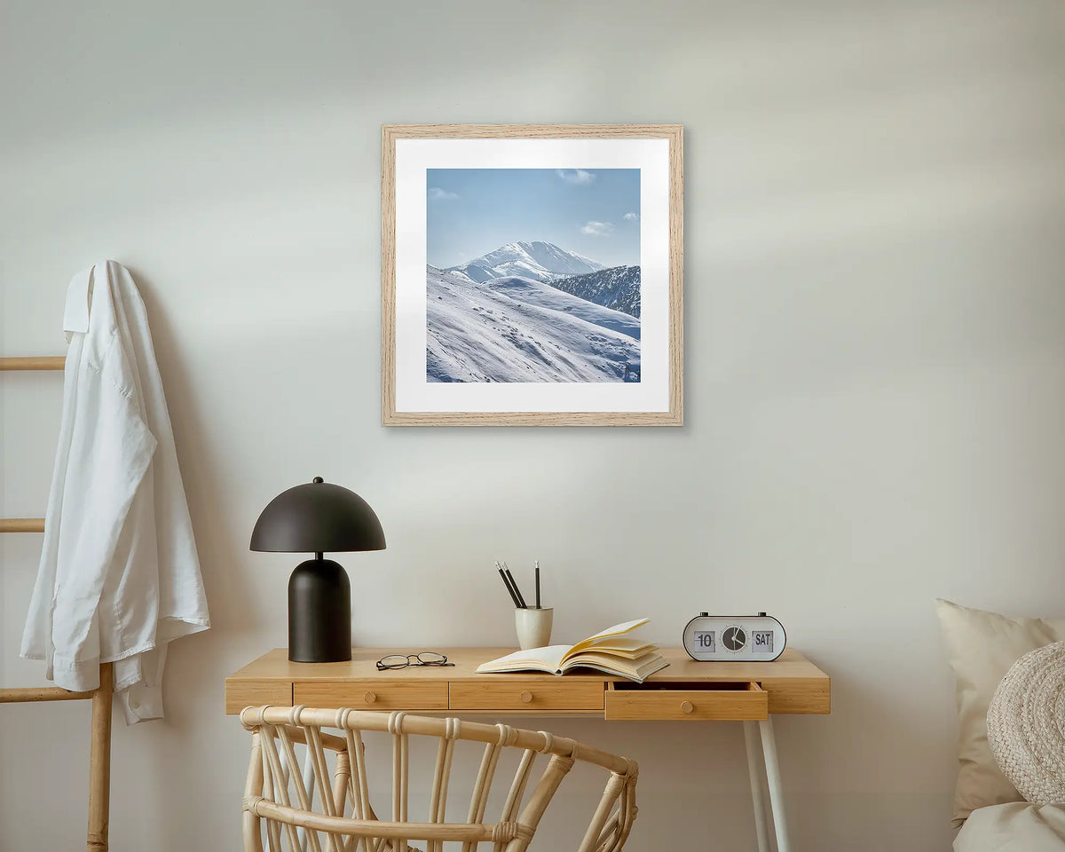 Icon Of The Alps. Mount Feathertop framed wall art print, with an oak frame, above a bedside table. 