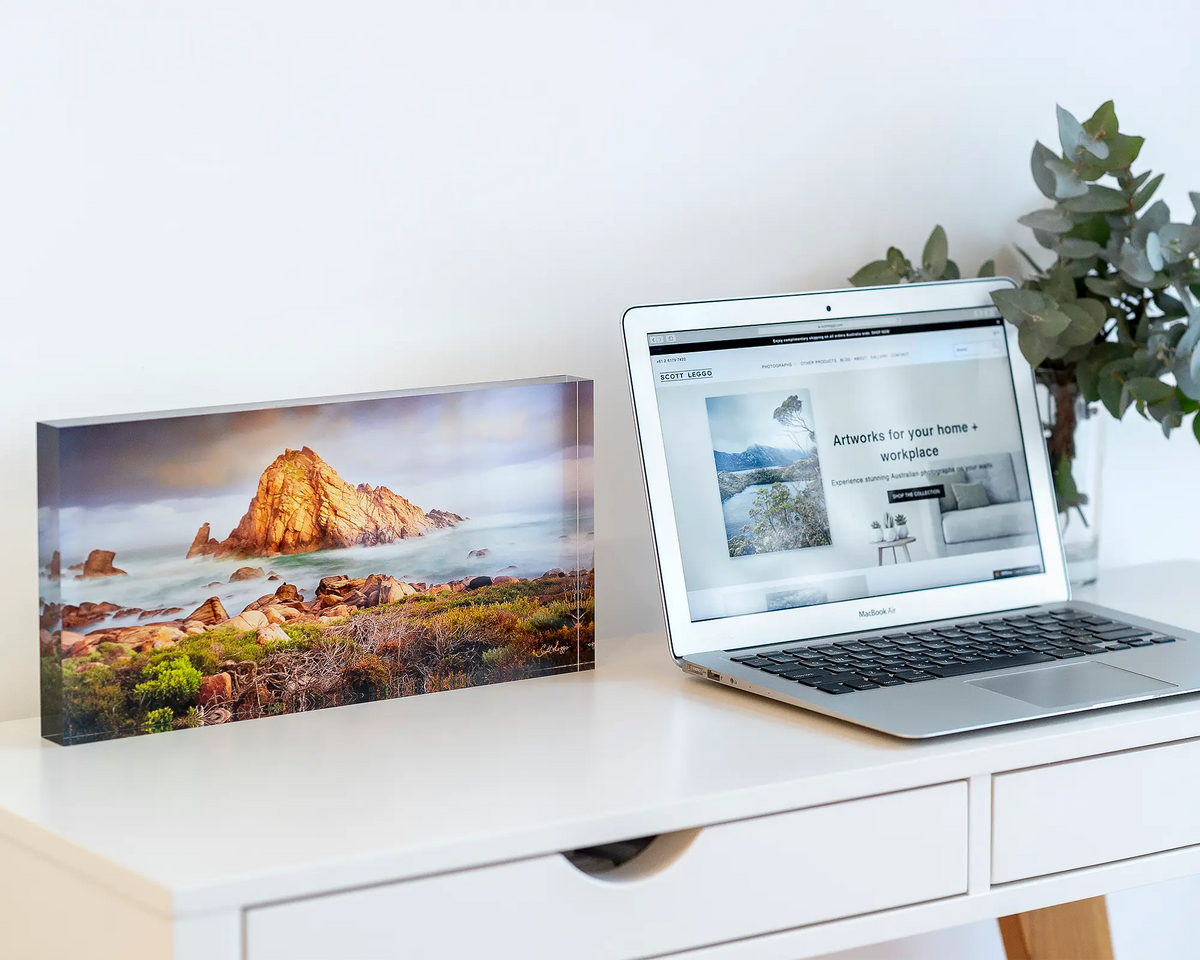 Icon of the South West acrylic block displayed next to a laptop. 