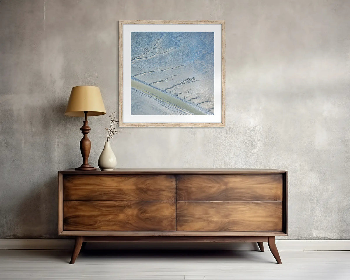 Increment. Square, abstract wall art print, with a timber frame, above a side table. 