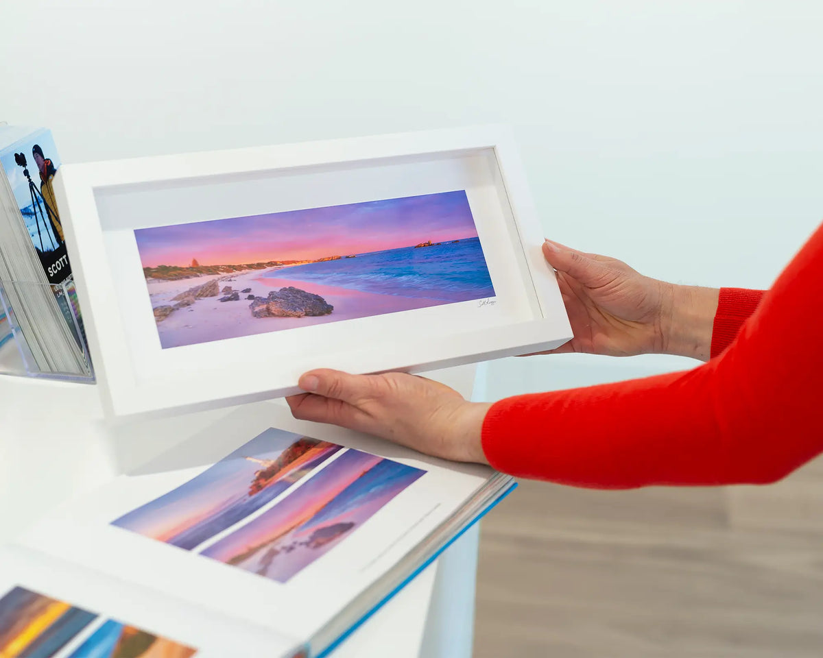 Island Getaway. Picturesque beach, small framed print, with a white frame and a book.