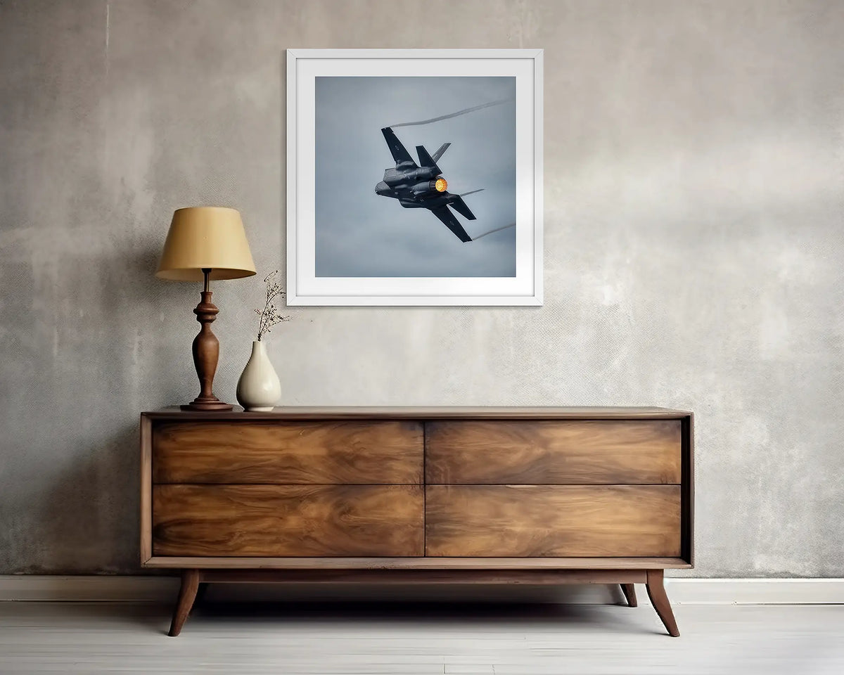 Lit. F-35 jsf wall art print, with a white frame, above a side table. 