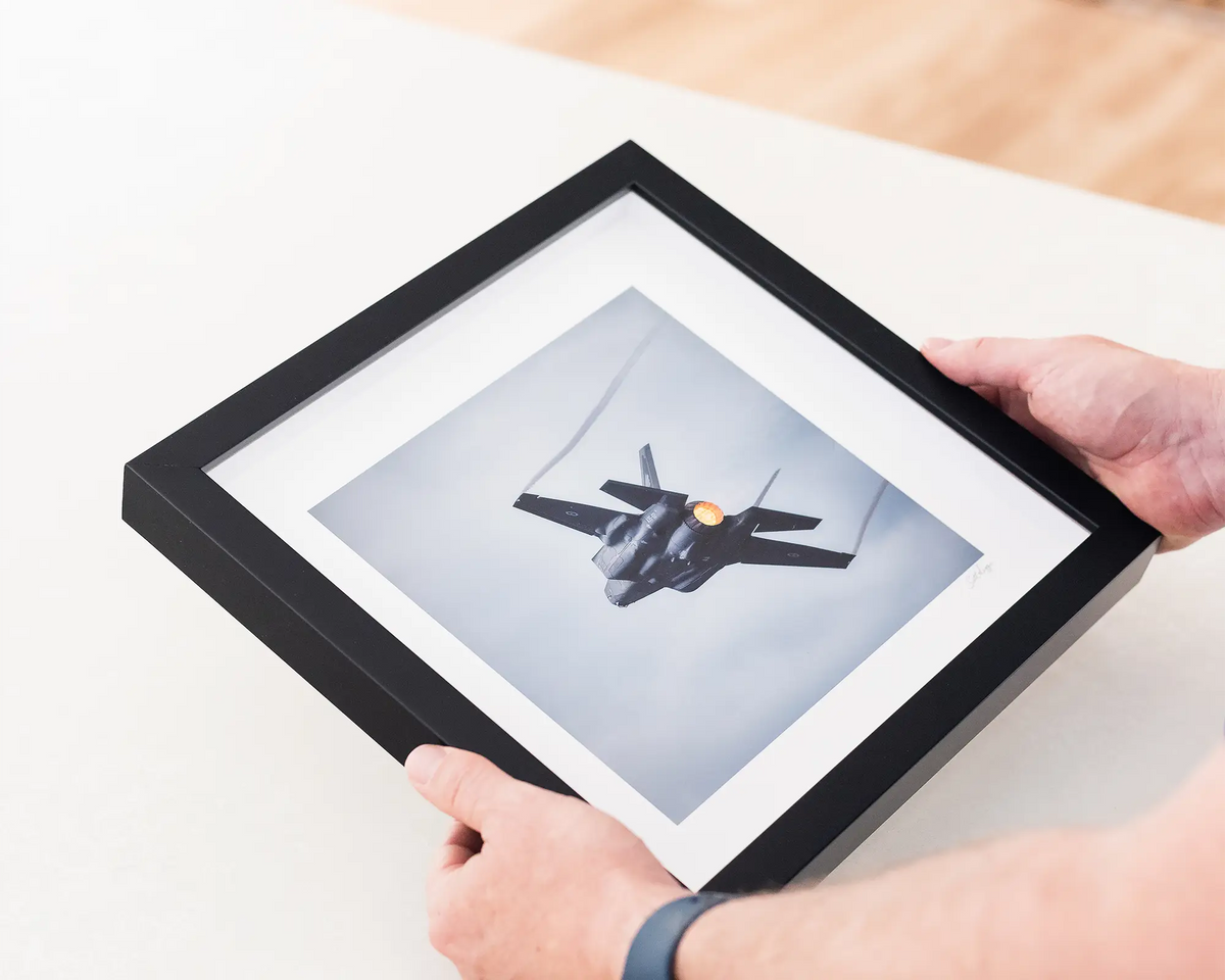 Lift. F-35 lightning in flight. Small framed print with black frame being held.