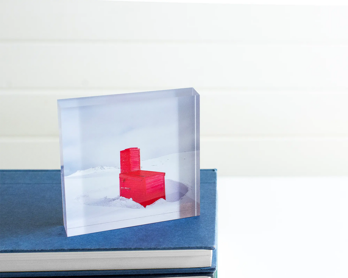 Little Red acrylic block sitting atop a  pile of books. 