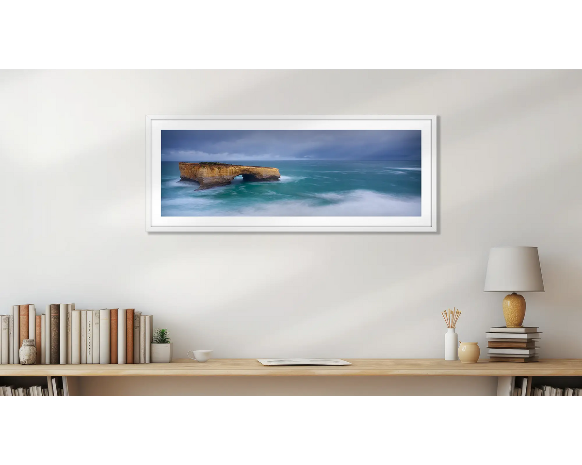 London Arch. Great Ocean Road wall art print, with a white frame, hung above a bookshelf. 