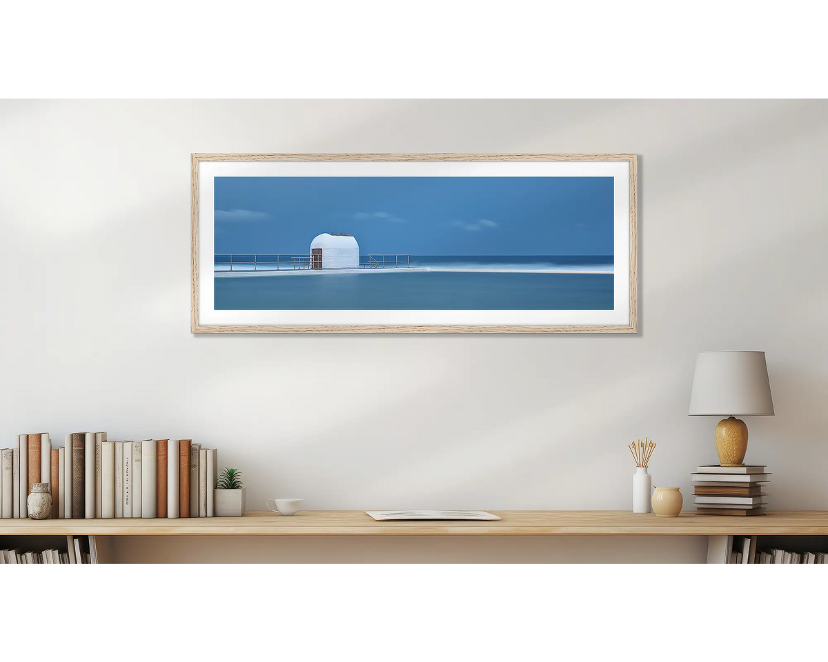 Merewether Calm. Wall art print of Merewether Baths in a Tasmanian oak frame, above a desk. 