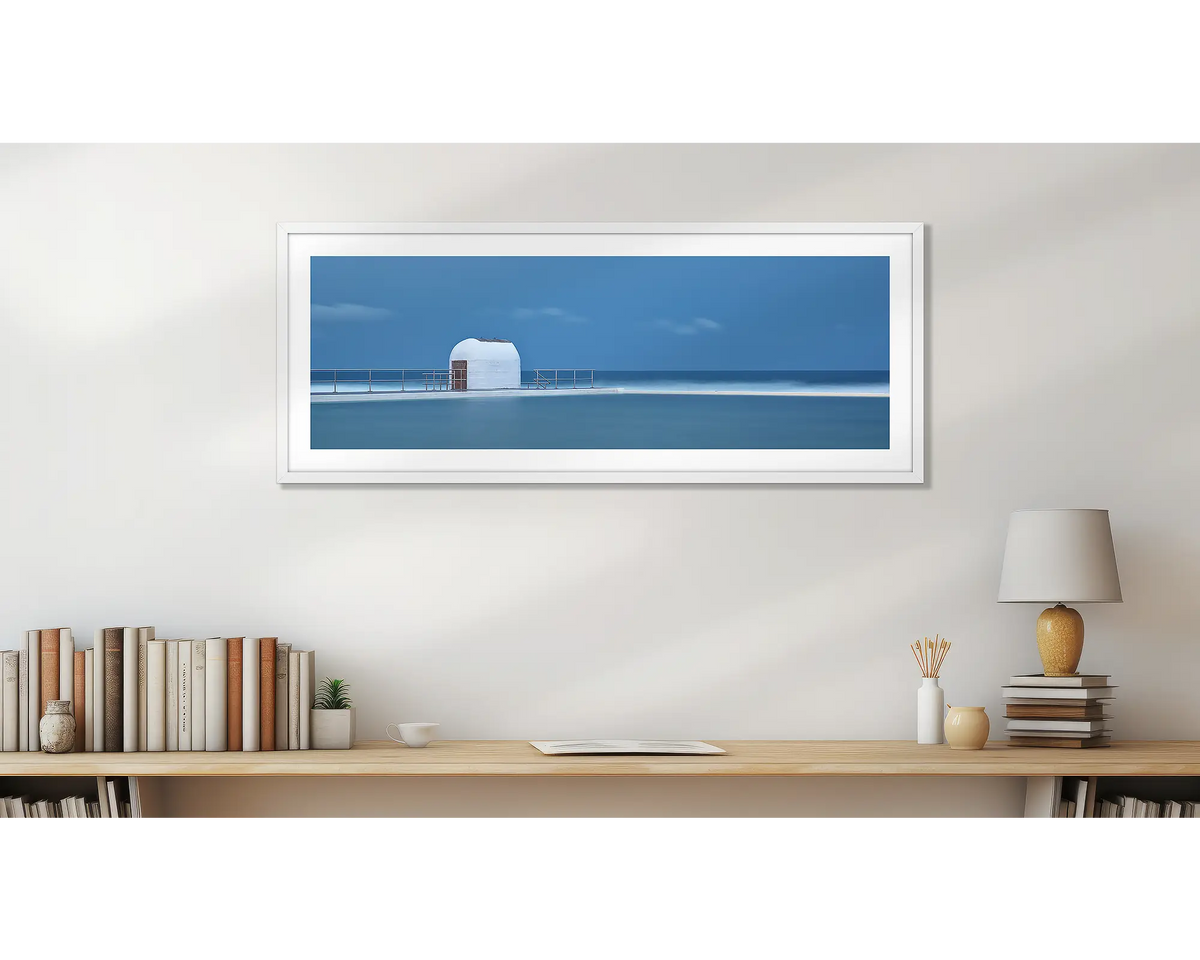 Merewether Calm. Wall art print of Merewether Baths in a white frame, above a desk. 