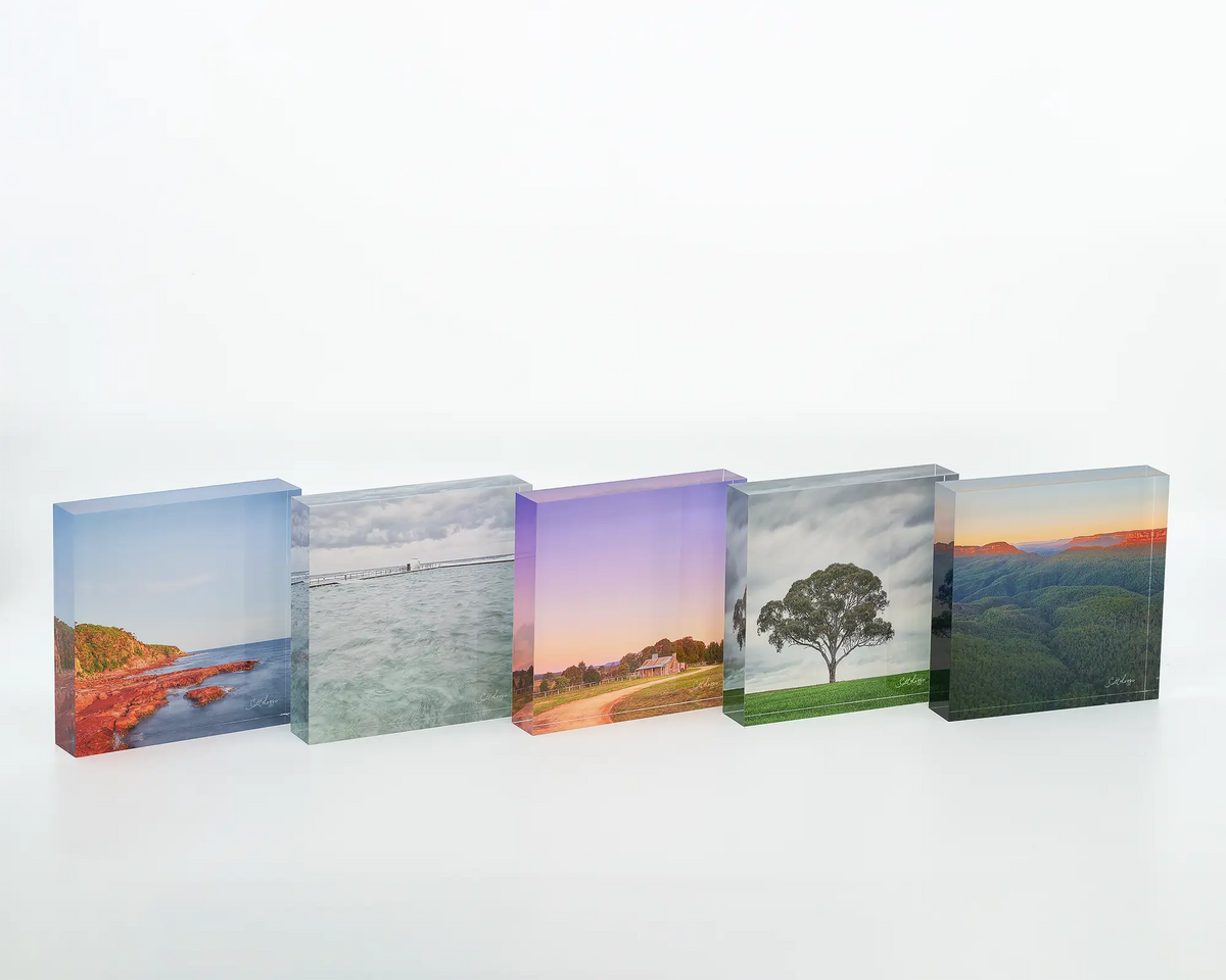 Moody Merewether acrylic block displayed on a desk next to other square acrylic blocks. 