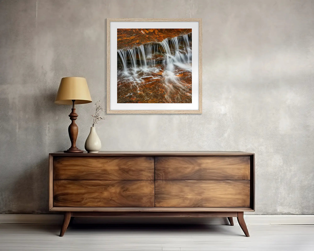 Motion. Square, waterfall wall art print, with a Tassie oak frame, above a side table. 