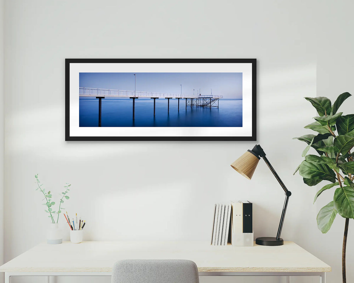 Nightcliff Jetty. Darwin sunrise, framed wall art print, in a black frame, hanging above a desk.