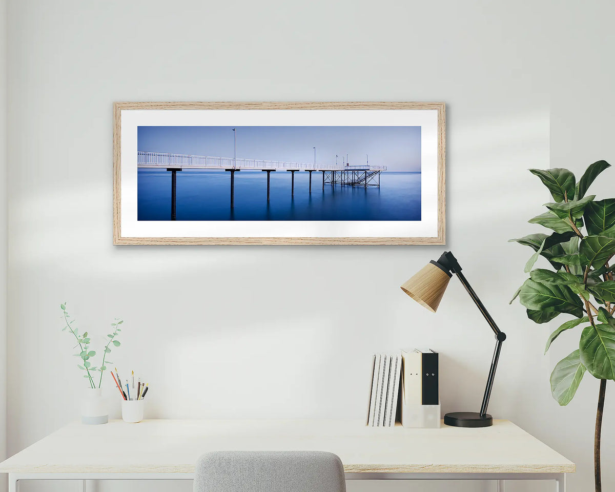 Nightcliff Jetty. Darwin sunrise, framed wall art print, in an oak frame, hanging above a desk.