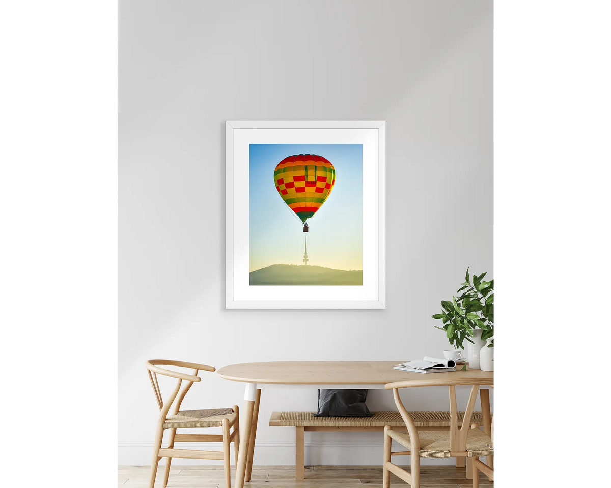 On Top. Canberra balloon artwork with a white frame, above a table.