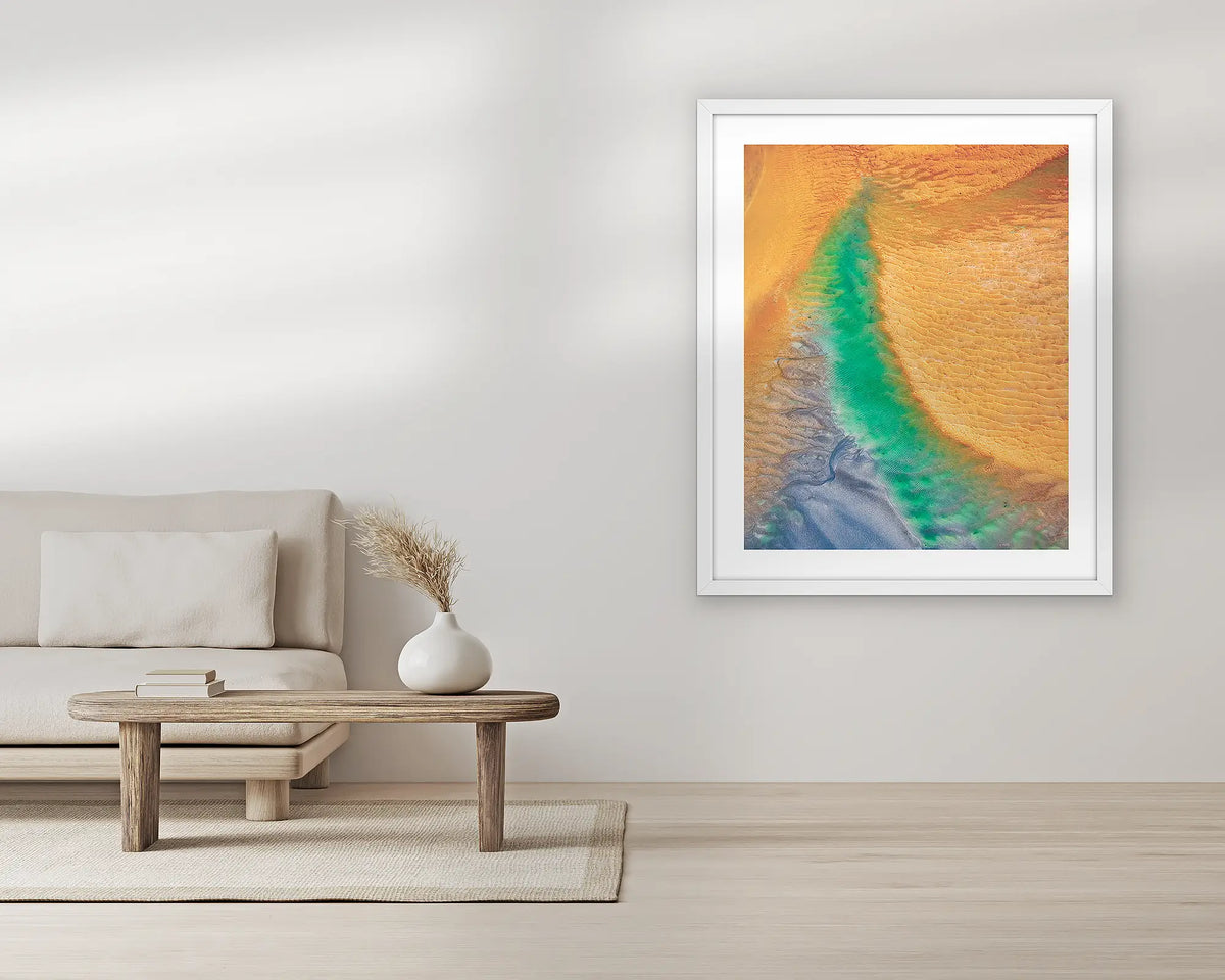 Opal Illusion. Aerial wall art print, with a white frame, in a living room. 