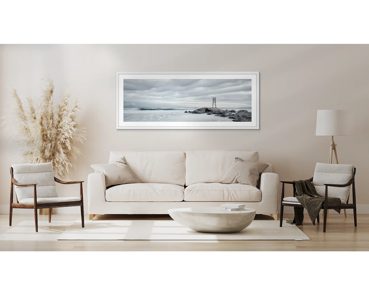 Pacific View. Newcastle wall art, in a white frame, above a couch. 