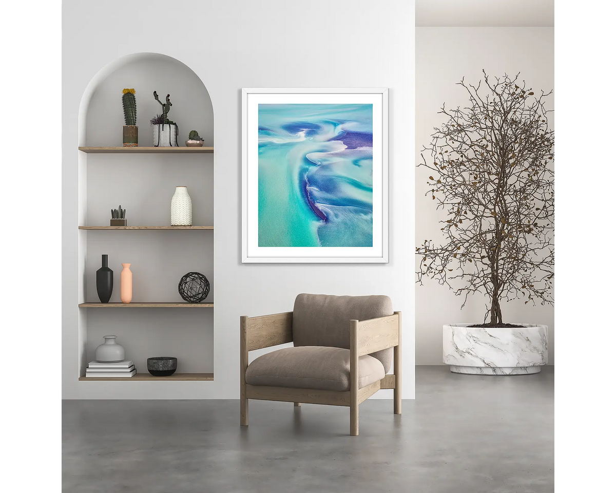 Permeate. Aerial abstract wall art print with white frame hung above chair.